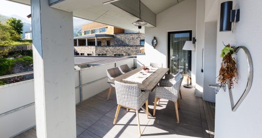 Großzügige und überdachte Terrasse mit Sitzgruppe und Tisch für 4 Personen und Zugang zur Wohnküche
