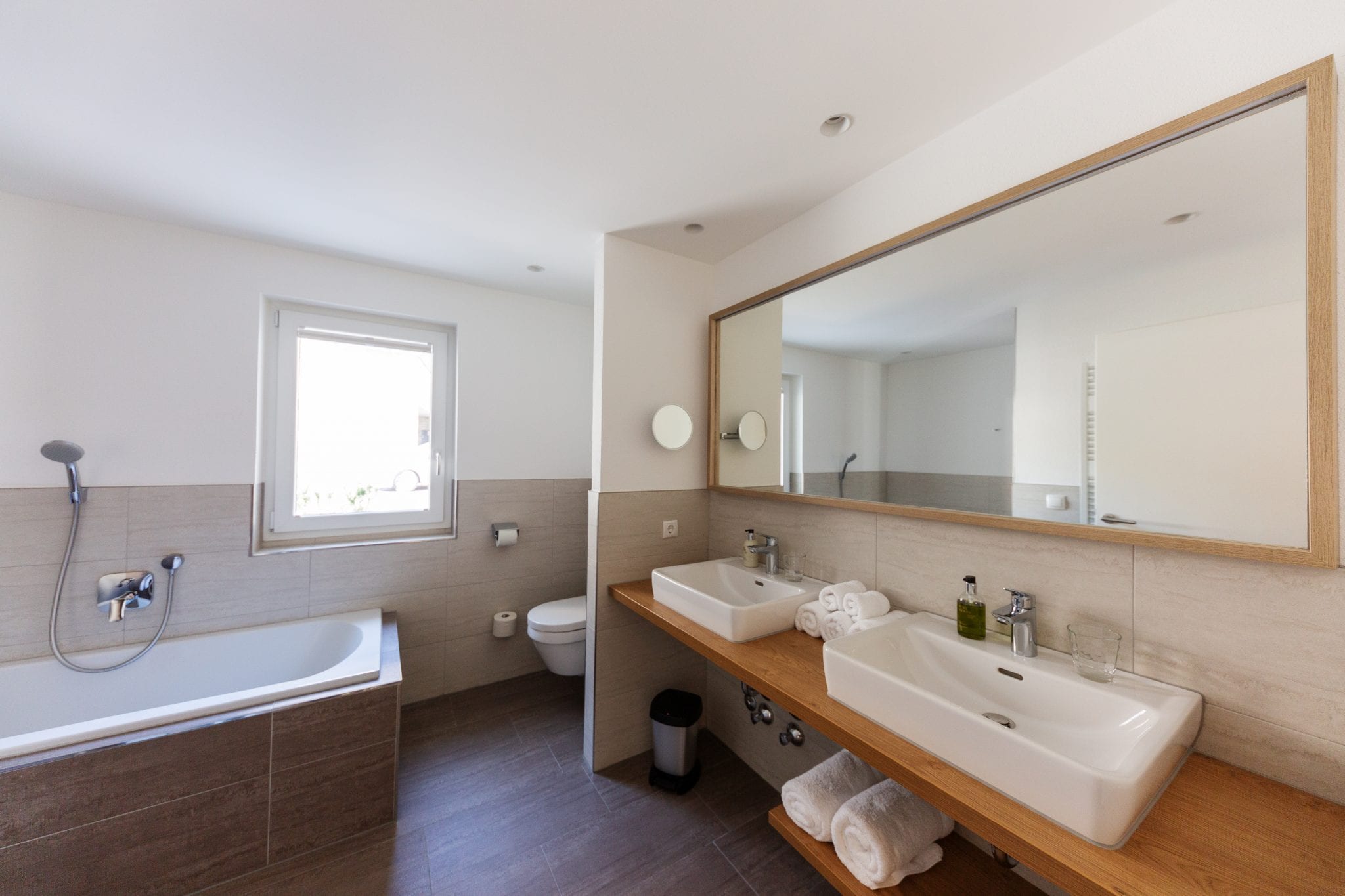 Hauptbadezimmer mit 2 Waschbecken, Dusche, Toilette, Badewanne und Fenster – Family Apartment da Peatala Apartments Serfaus Sommer