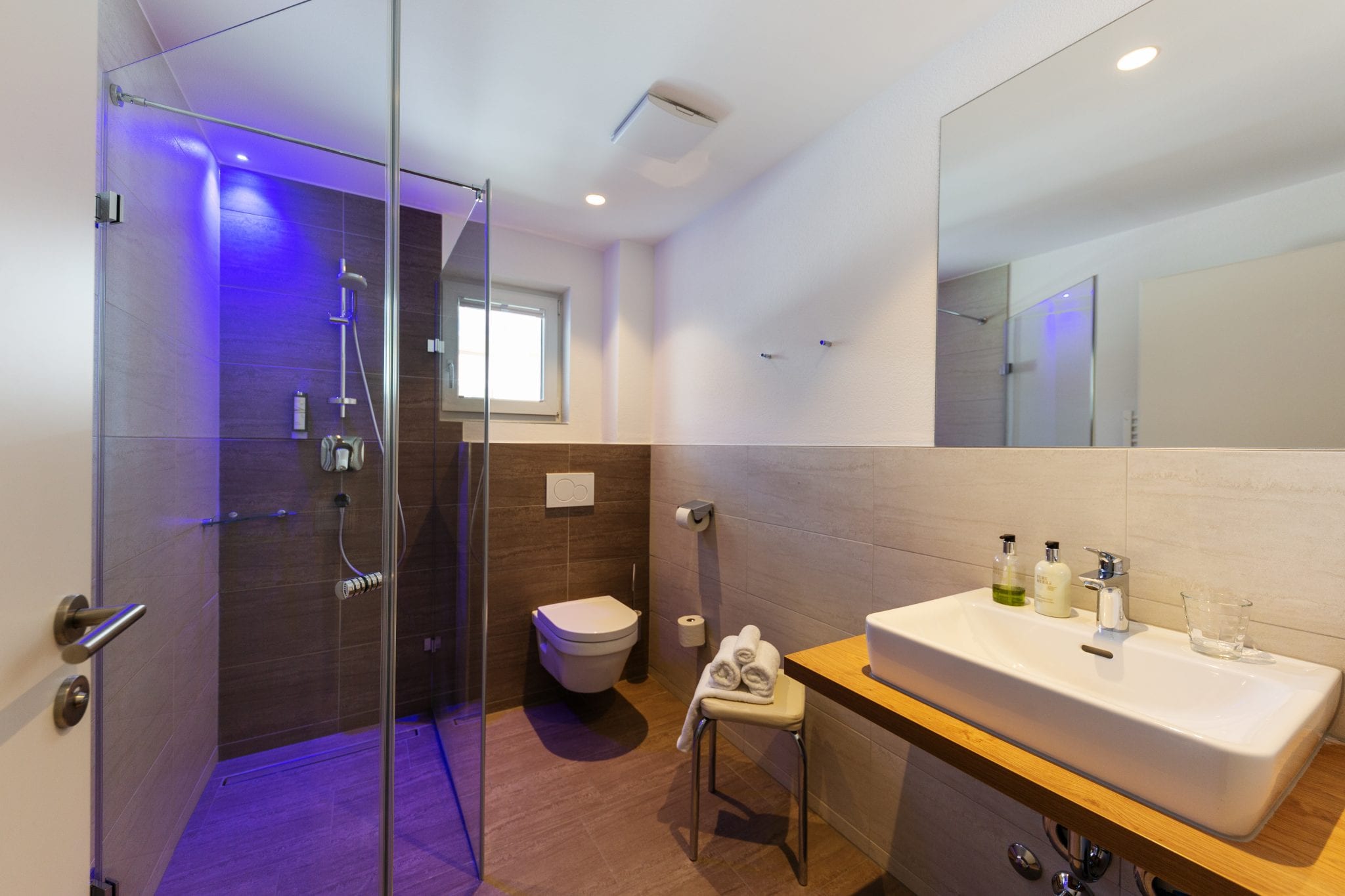 Zweites Badezimmer mit Waschbecken, Dusche, Toilette, Handtuchtrockner und Fenster – Family Apartment da Peatala Apartments Serfaus Sommer
