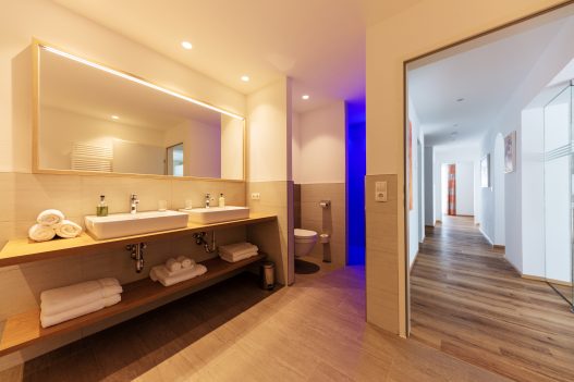 Großes Badezimmer mit 2 Waschbecken, abgetrennter Dusche und Toilette in entspannten blauen Licht