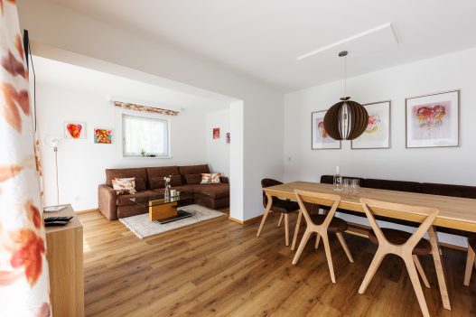 Esstisch für 6 Personen aus hellem Holz im naturbezogenen Ambiete und angrenzendes Wohnzimmer