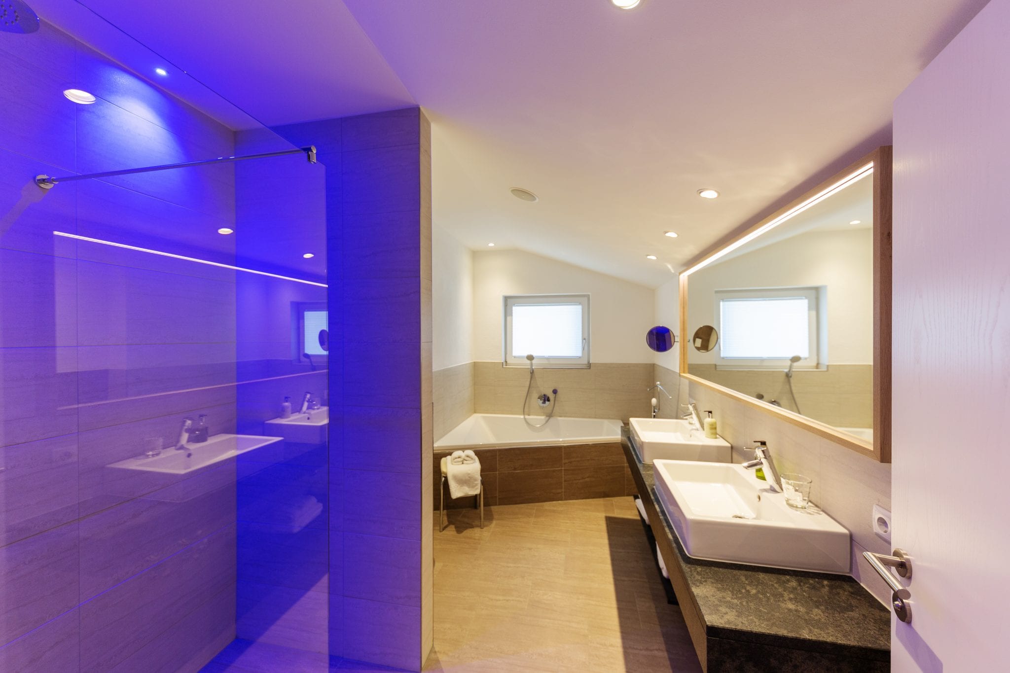 Badezimmer mit Badewanne, zwei Waschbecken, Toilette und Glasdusche – Lifestyle Apartment da Peatala Apartments Serfaus Sommer