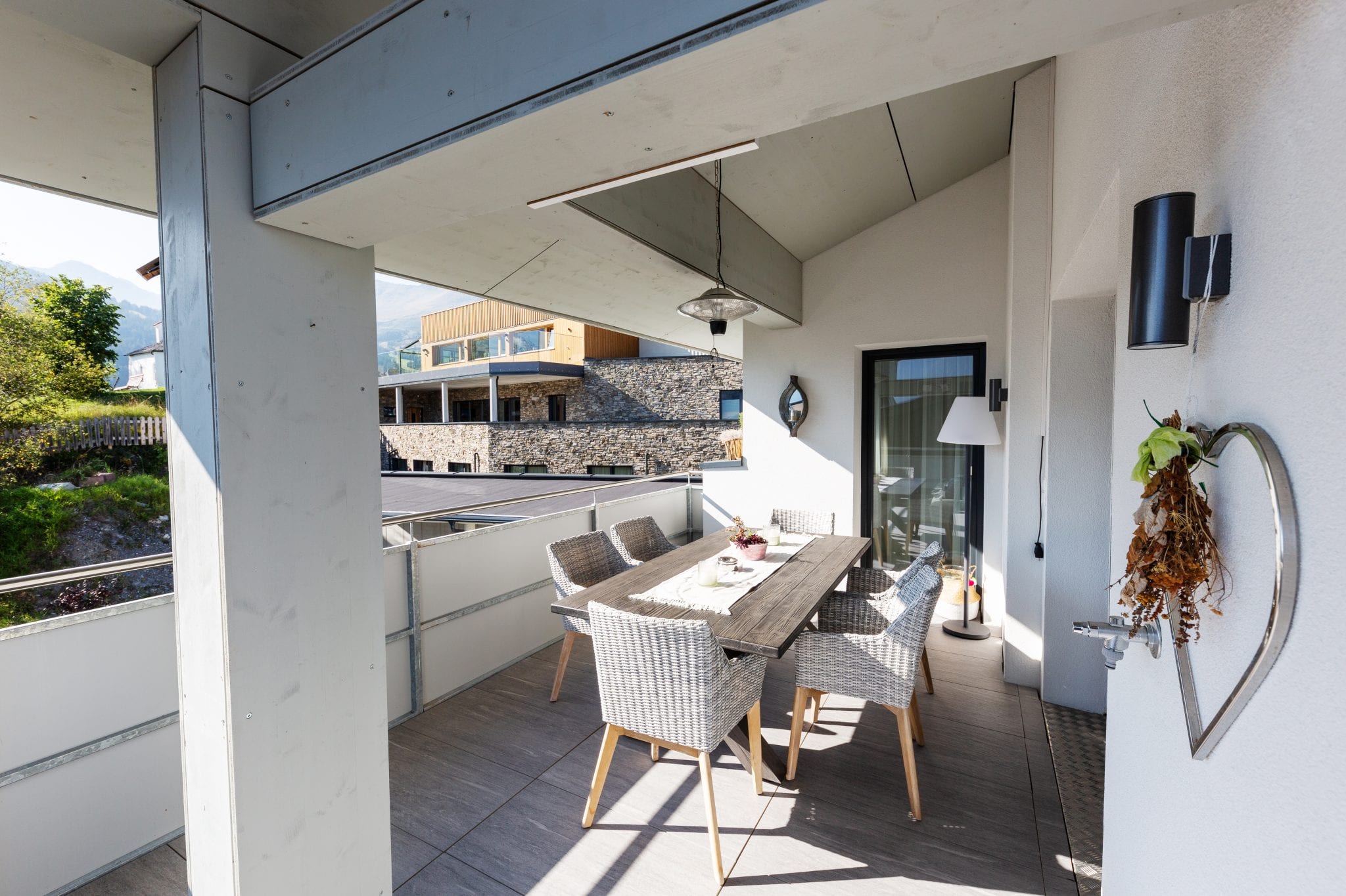 Überdachte Terrasse mit Sitzgruppe und Tisch für 6 Personen und Zugang zur Wohnküche – Lifestyle Apartment da Peatala Apartments Serfaus Sommer