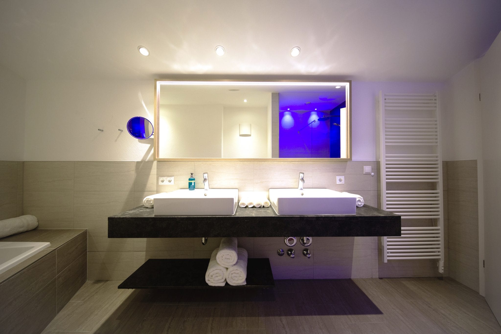 Badezimmer mit zwei Waschbecken, großem Spiegel und Handtuchtrockner – Lifestyle Apartment da Peatala Apartments Serfaus Sommer