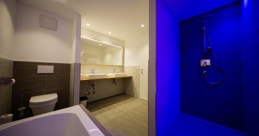 Badezimmer mit 2 Waschbecken, abgetrennte Dusche, Toilette, Badewanne und Fenster für Tageslicht