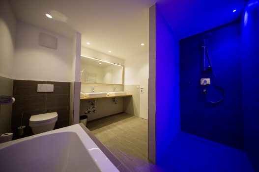 Badezimmer mit 2 Waschbecken, abgetrennte Dusche, Toilette, Badewanne und Fenster für Tageslicht