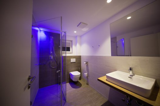 Zweites Badezimmer mit Waschbecken, Dusche, Toilette, Handtuchtrockner und Fenster für Tageslicht