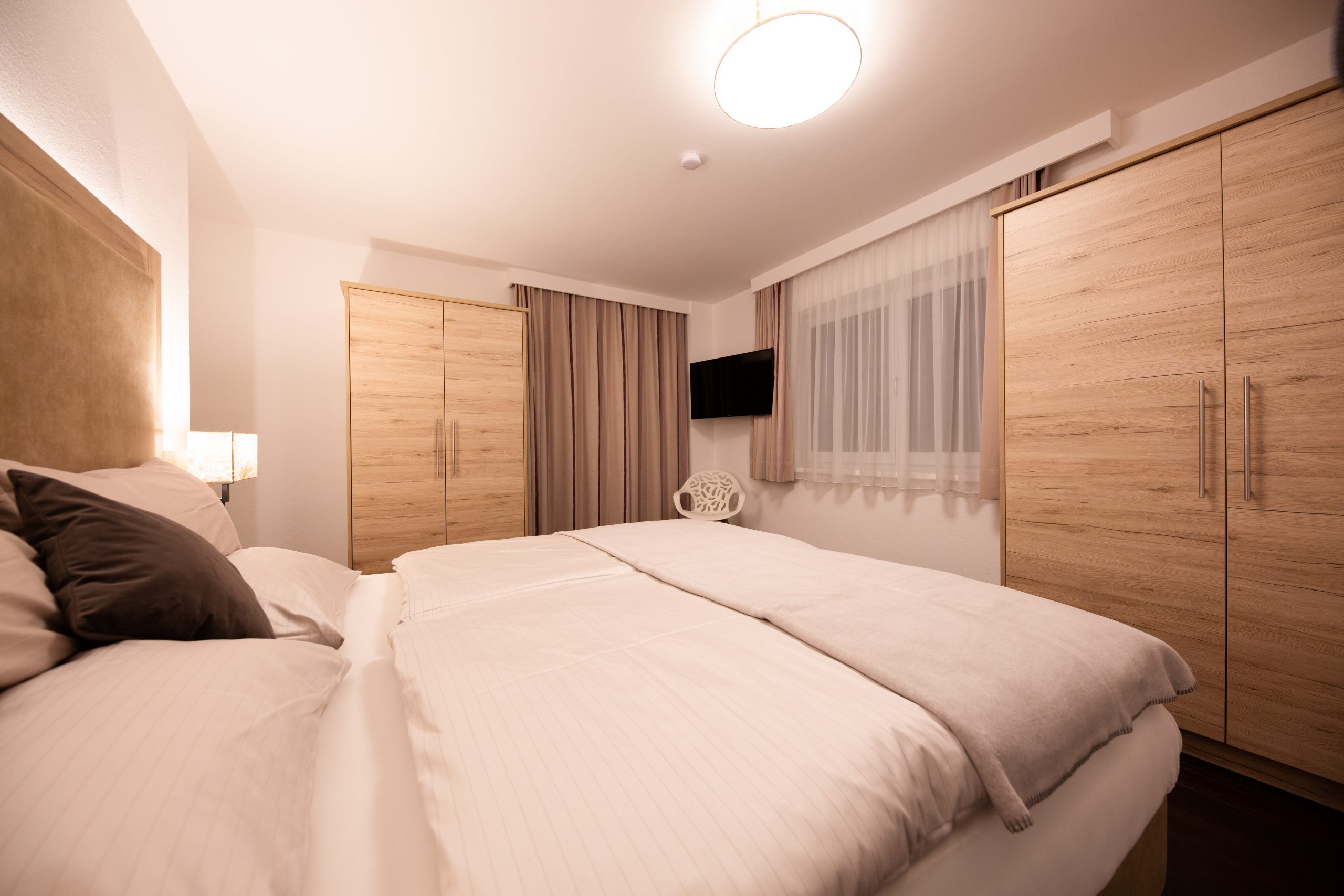 Schlafzimmer West mit Doppelbett, Allergikerbettwäsche, Einbauschrank, TV und Leselampe – Family Apartment da Peatala Apartments Serfaus Winter