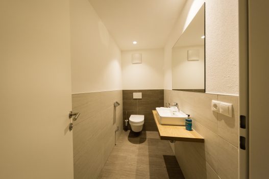 Separates WC mit Sitztoilette und Pissoir. Toilettenpapier, Handseife und Creme wird bereitgestellt