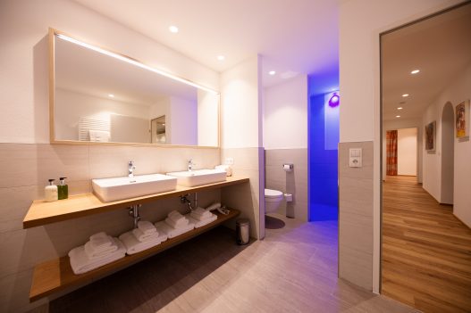 Großes Badezimmer mit 2 Waschbecken, abgetrennter Dusche und Toilette in entspannten blauen Licht