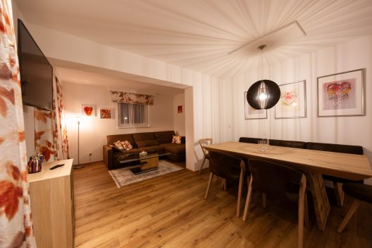 Esstisch für 6 Personen aus hellem Holz im naturbezogenen Ambiete und angrenzendes Wohnzimmer