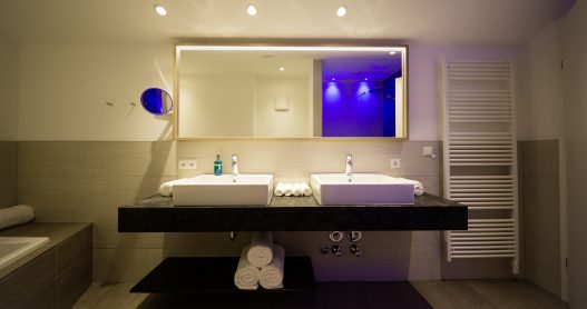 Zwei großzügige Waschbecken, großem Spiegel und Handtuchtrockner für Handtücher und Bademäntel