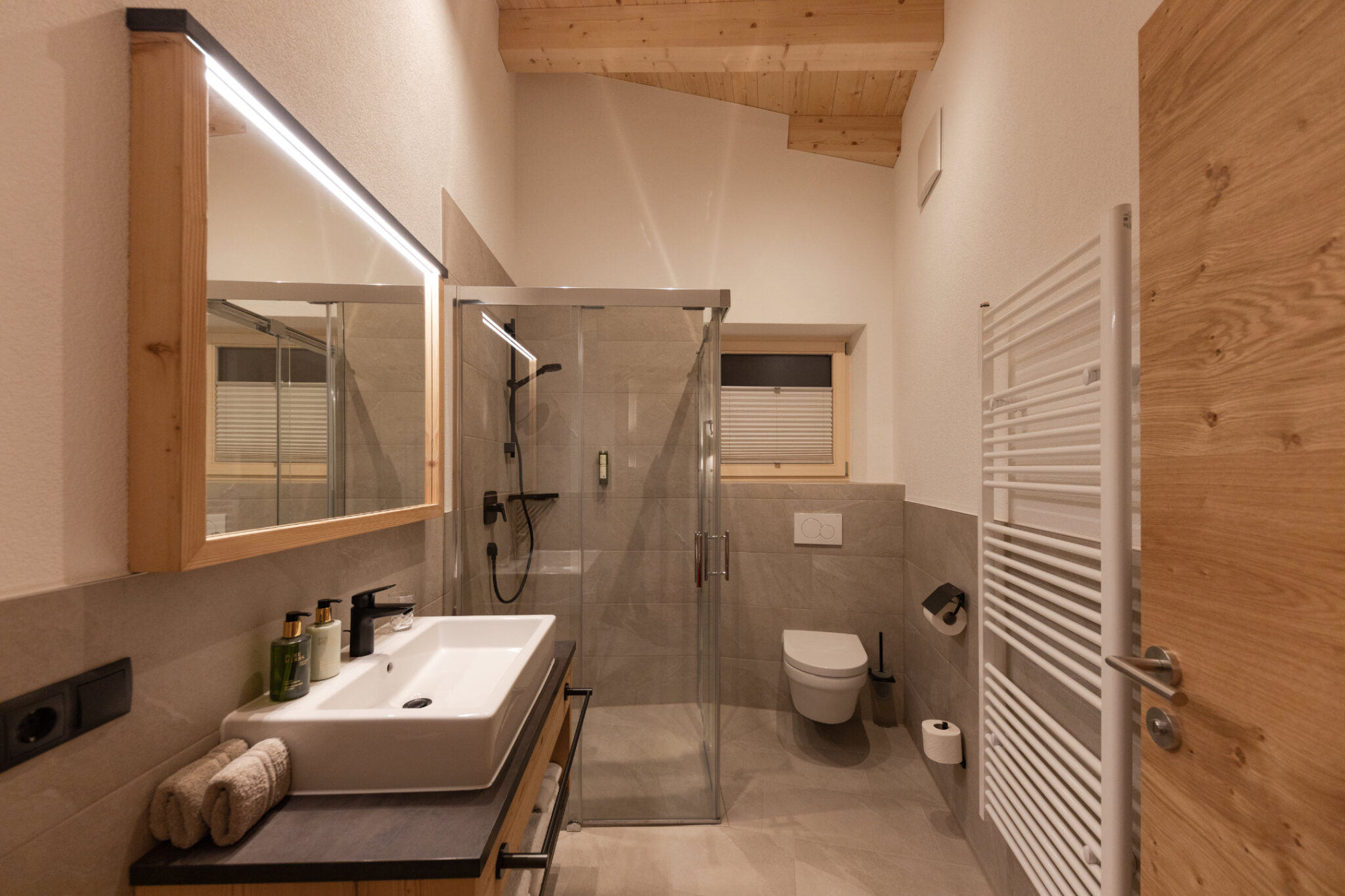 Badezimmer Obergeschoss mit Waschbecken, Spiegel und Dusche – Mountain Chalet da Peatala Apartments Serfaus Winter