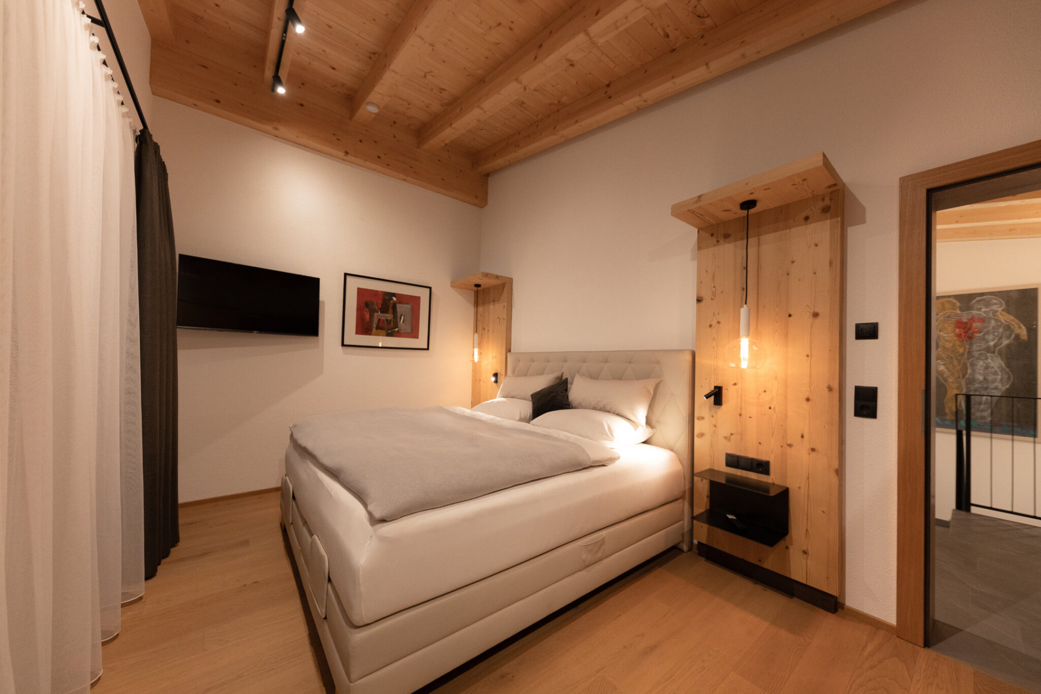 Schlafzimmer Obergeschoss mit Doppelbett, Nachttischen, Fernseher und Balkon – Mountain Chalet da Peatala Apartments Serfaus Winter