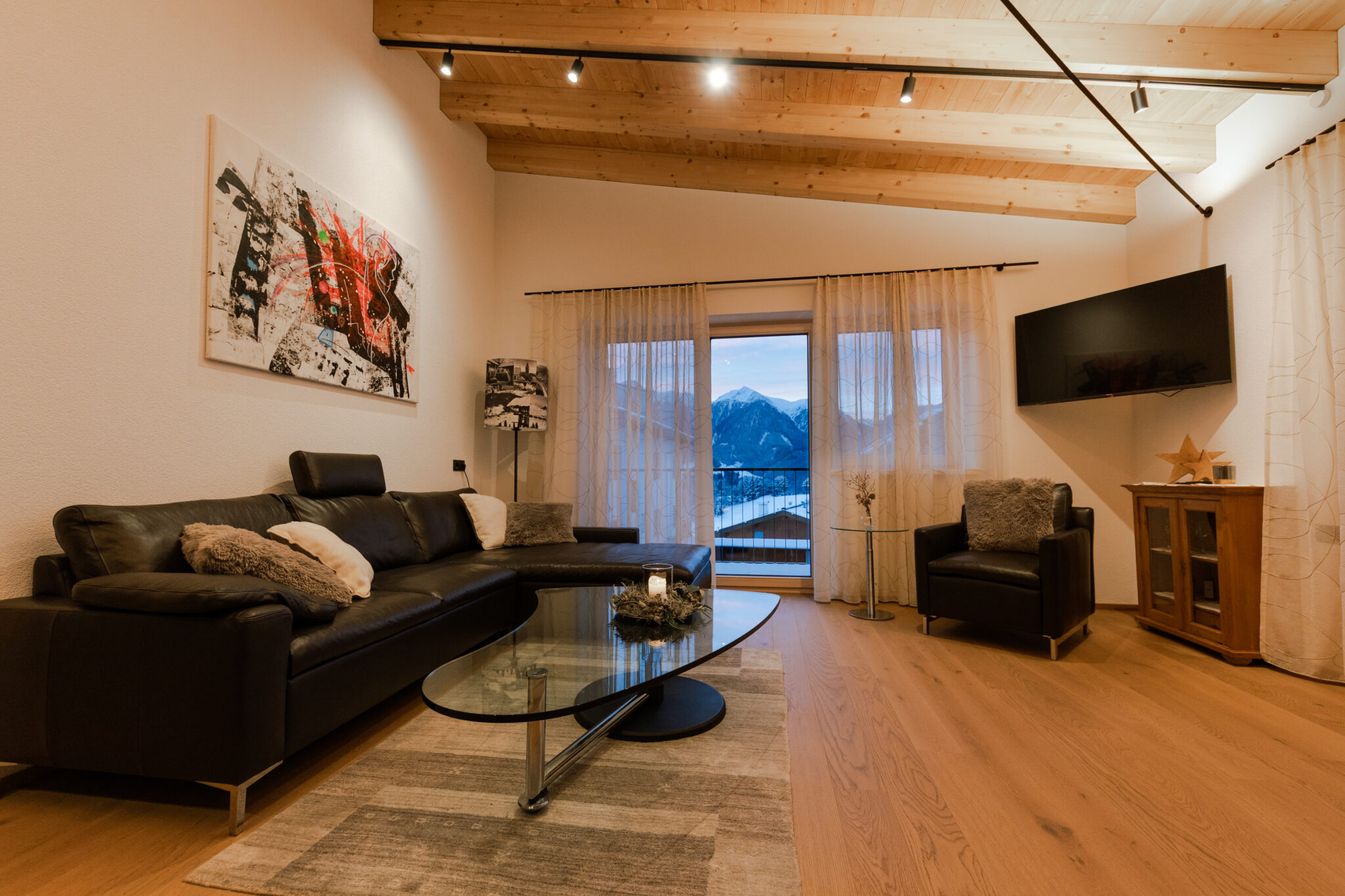 Wohnzimmer mit Sofa, Sessel, Couchtisch, Fernseher und Winterausblick – Mountain Chalet da Peatala Apartments Serfaus